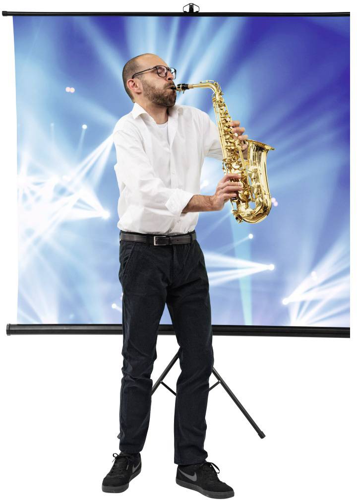 Muž hraje na saxofon před modrým pozadím s světelnými efekty. Má na sobě bílou košili a černé kalhoty.