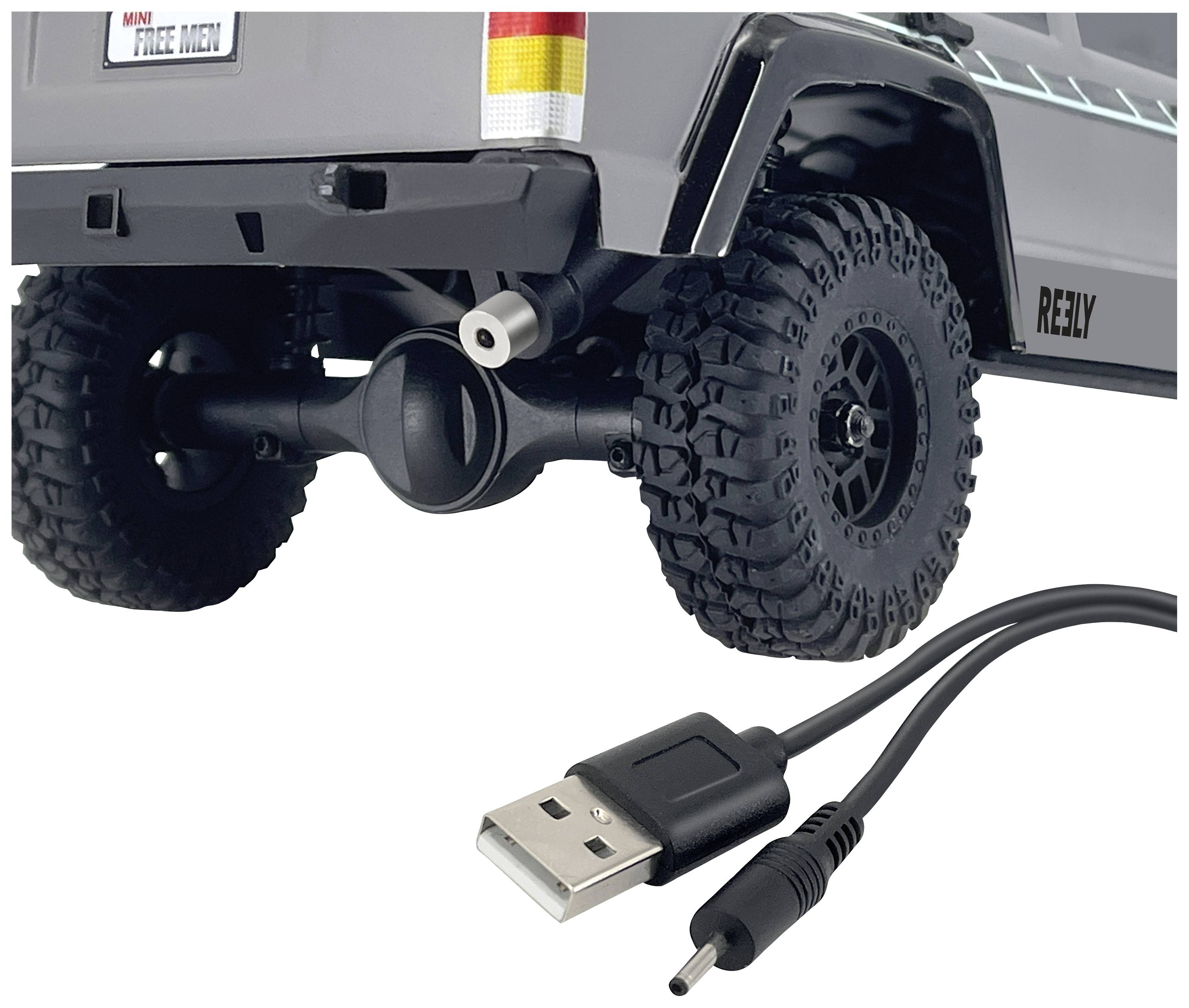 Zadní strana šedého hračkového terénního vozu s velkými koly je vidět. Dole je zobrazen USB kabel.