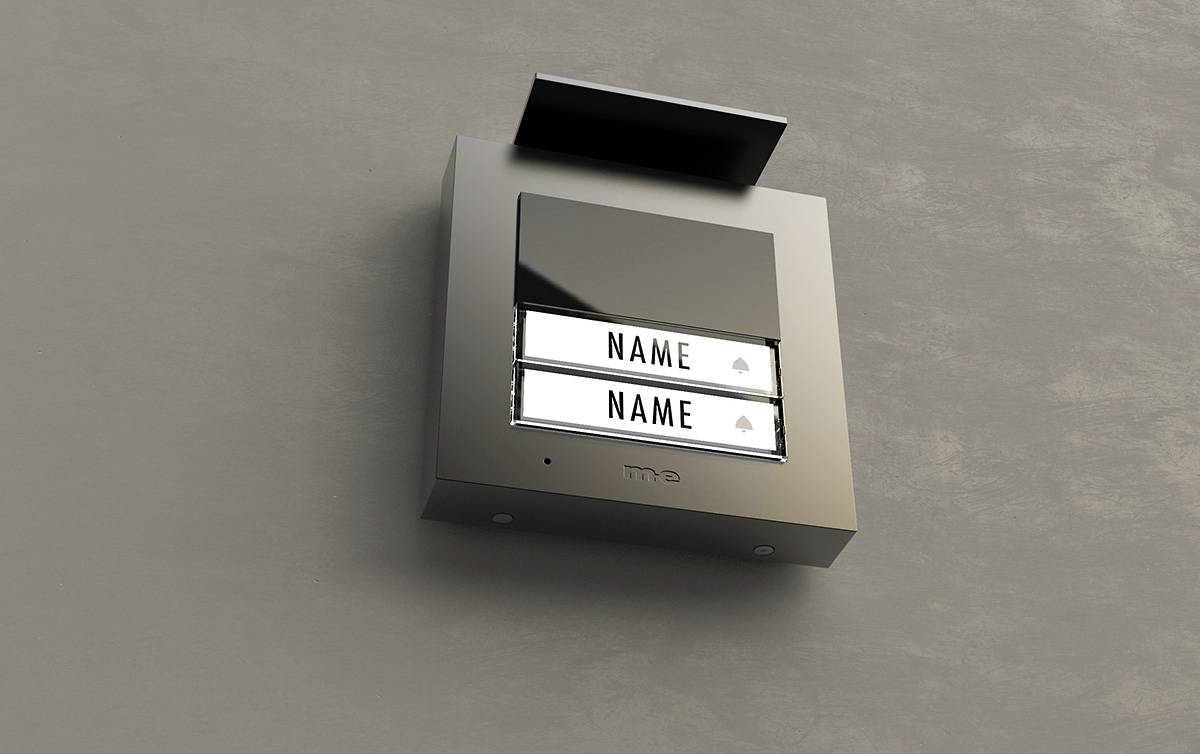 Štítek zvonku s dvěma jmenovkami na šedé zdi. Design působí moderně a elegantně.