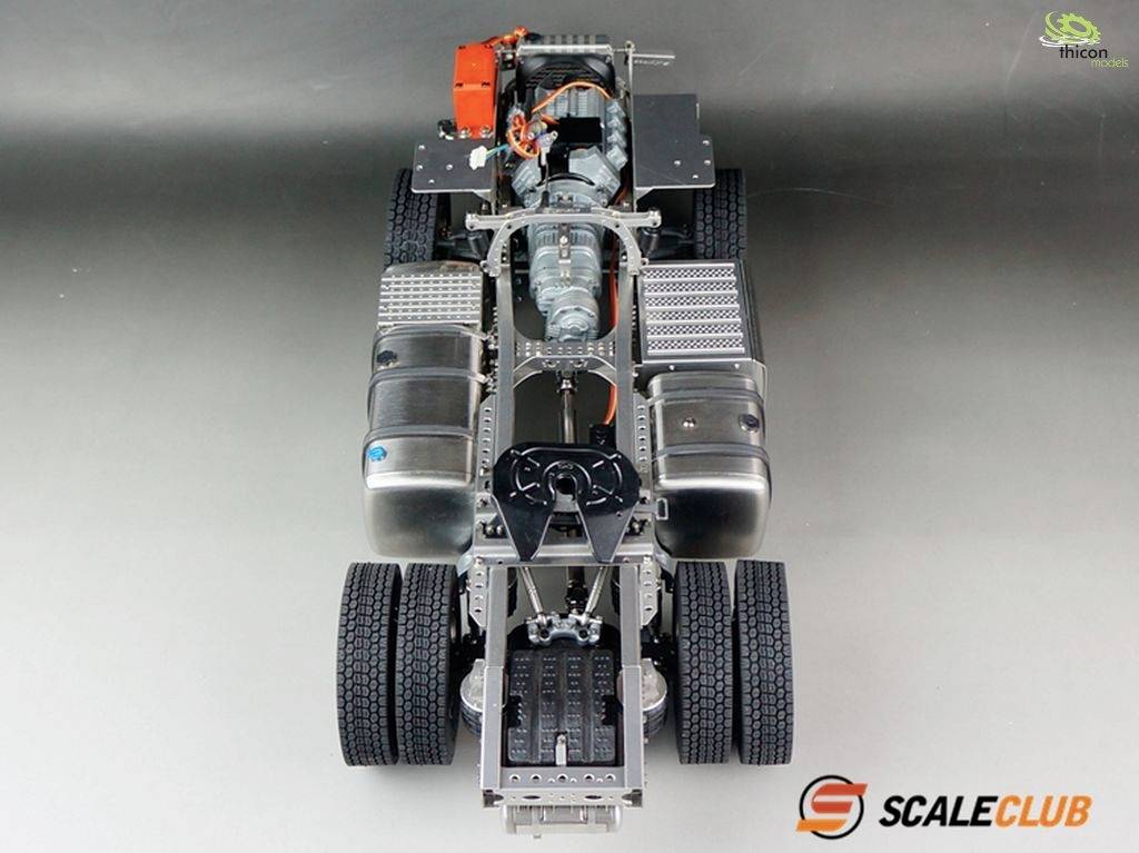 Model podvozku nákladního vozu zobrazuje detailní komponenty včetně motoru a elektroniky. Pohled shora na kola a centrální konstrukční prvky.