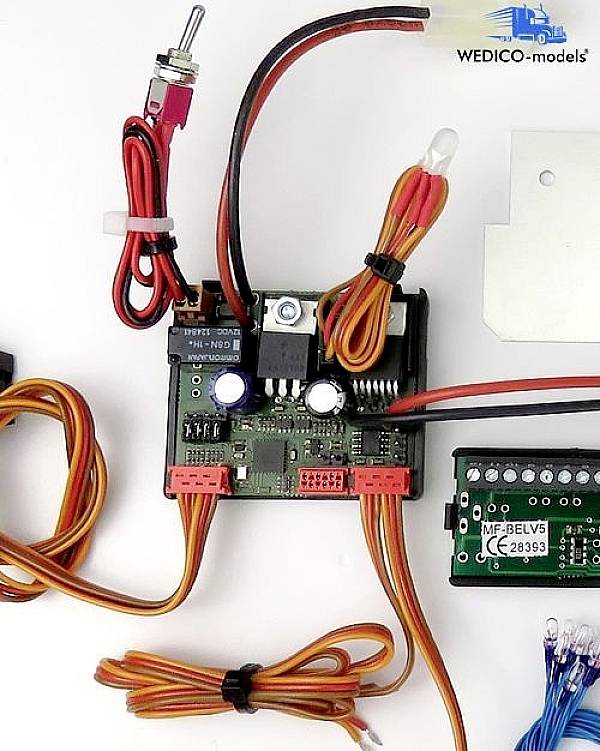 Detailní záběr elektronické řídicí desky s několika kabely a konektory, zasazený do kontextu modelářství.