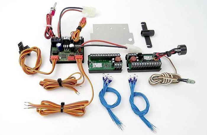 Elektronické komponenty na bílém pozadí, sestávající z desek plošných spojů, kabelů a konektorů, vhodné pro modelářství.