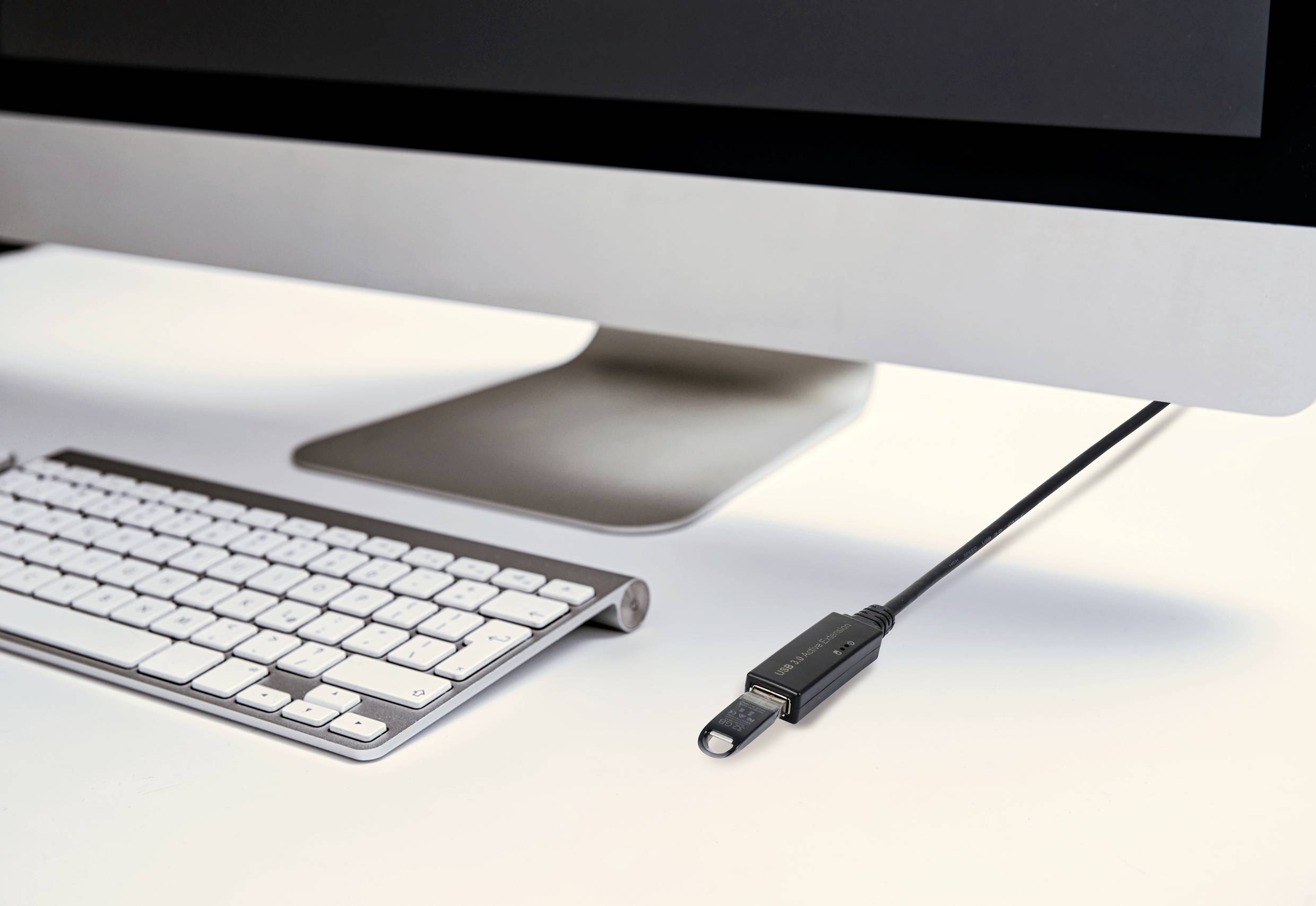 Počítačový monitor na psacím stole, před ním klávesnice a na straně monitoru zasunutý USB flash disk.