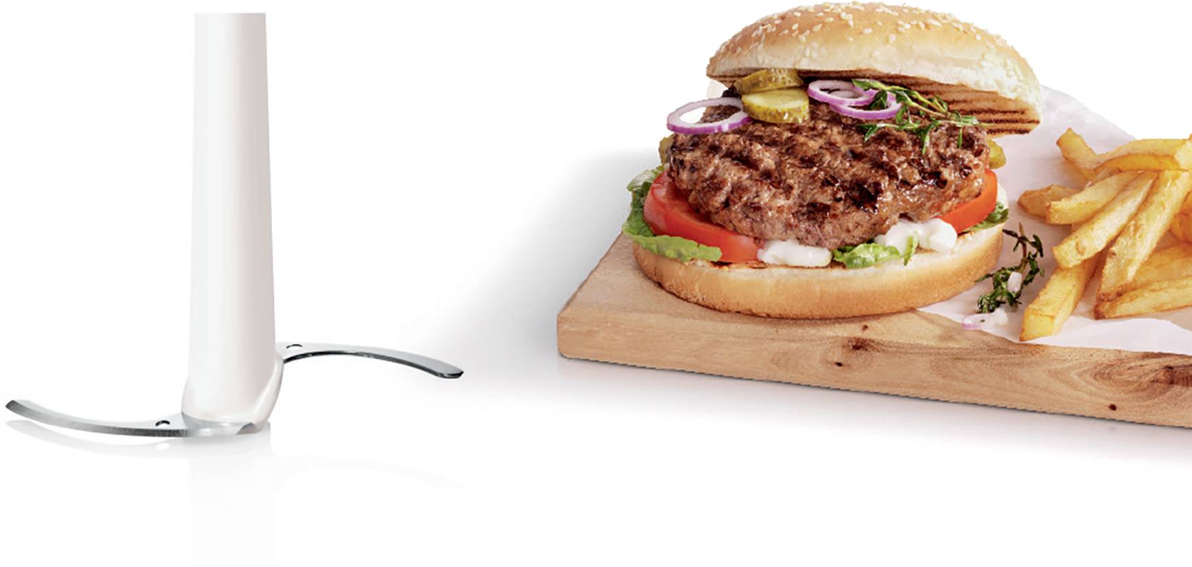 Burger s rajčaty, cibulí a salátem servírovaný na dřevěné desce, vedle porce hranolek a sklenice mléka.