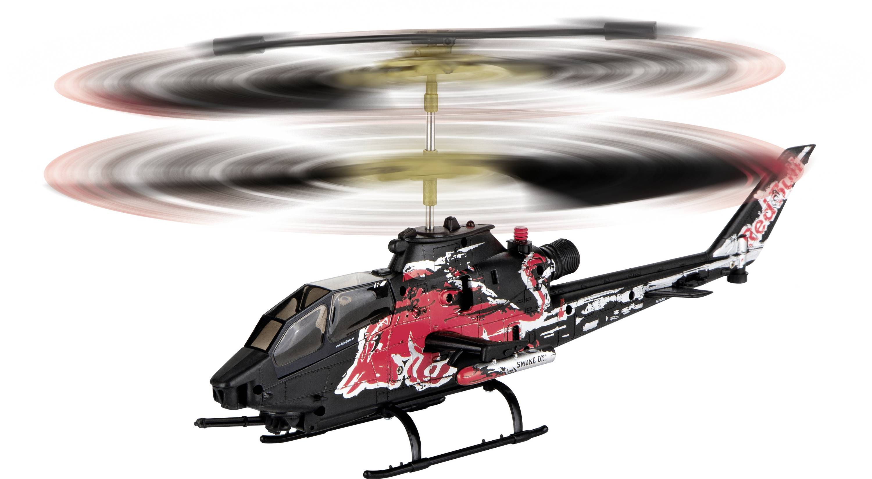 Dálkově ovládaná modelová helikoptéra ve vzduchu s logem červeného býka, rotory se rychle otáčejí, černé a červené barevné schéma.