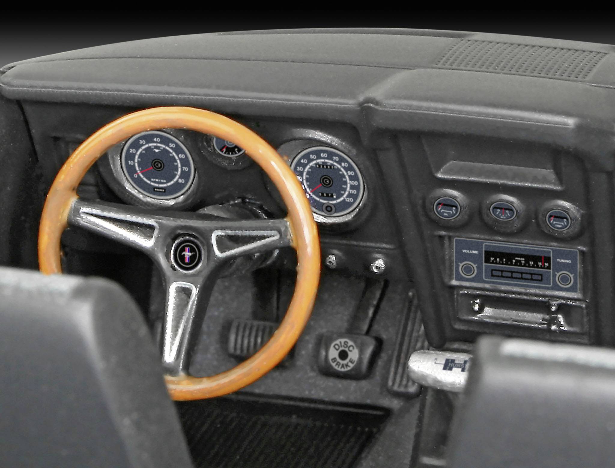Detailní záběr klasického autokokpitu s dřevěným volantem, přístrojovou deskou s analogovými přístroji a retro autorádiem.