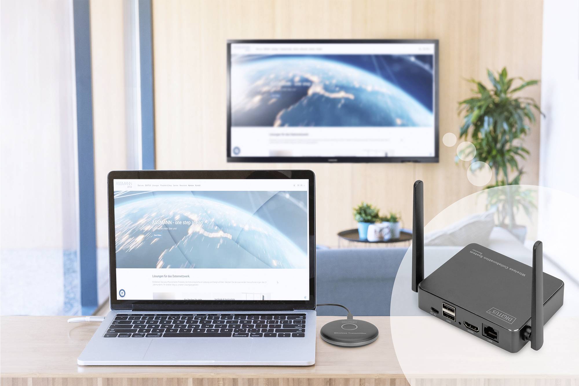 Laptop na stole zobrazuje mapu světa, bezdrátově se připojuje k zobrazenému televizoru v pozadí. V popředí zařízení Wi-Fi a přijímač.