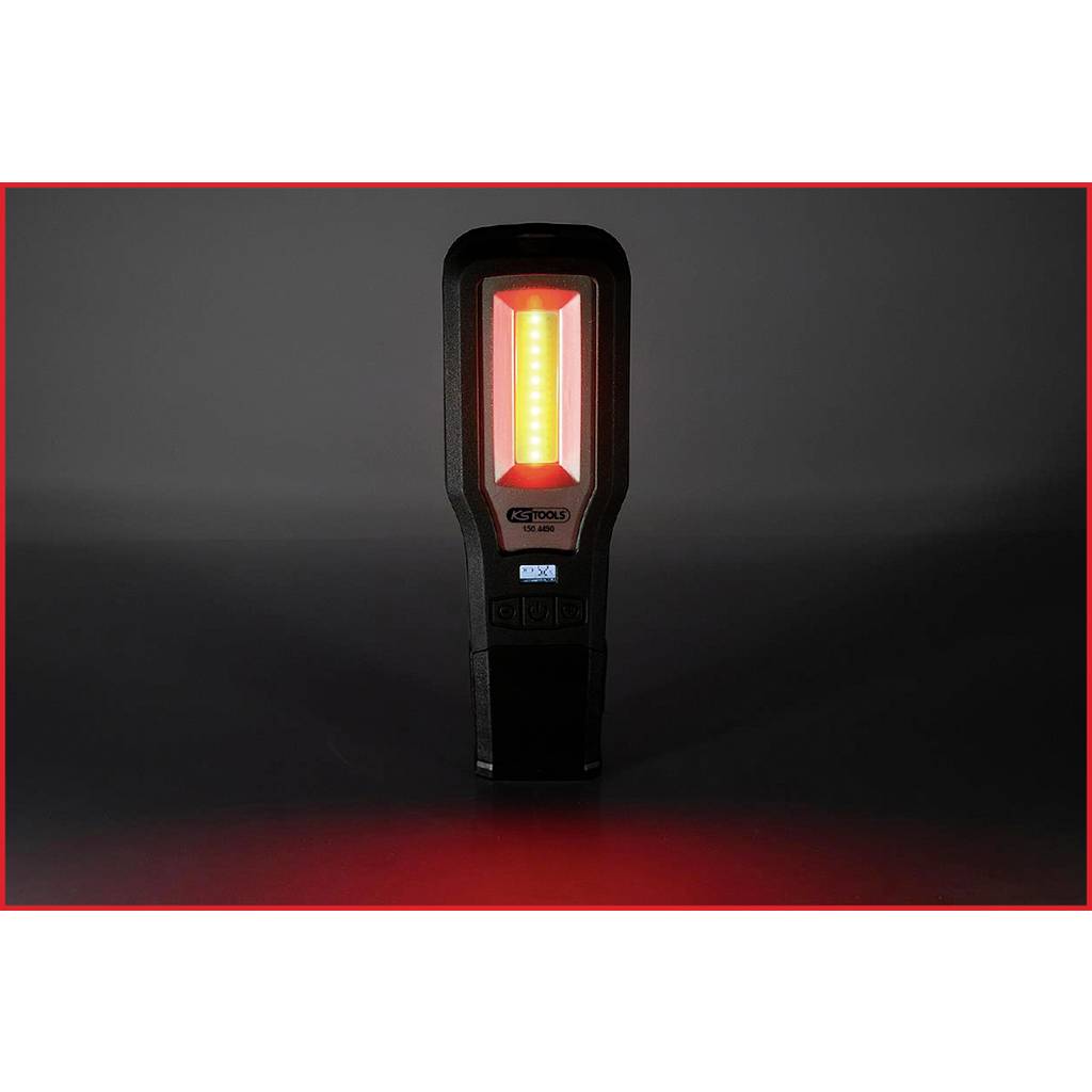 Přenosná pracovní lampa vyzařující červené světlo stojí vzpřímeně uprostřed tmavého pozadí.