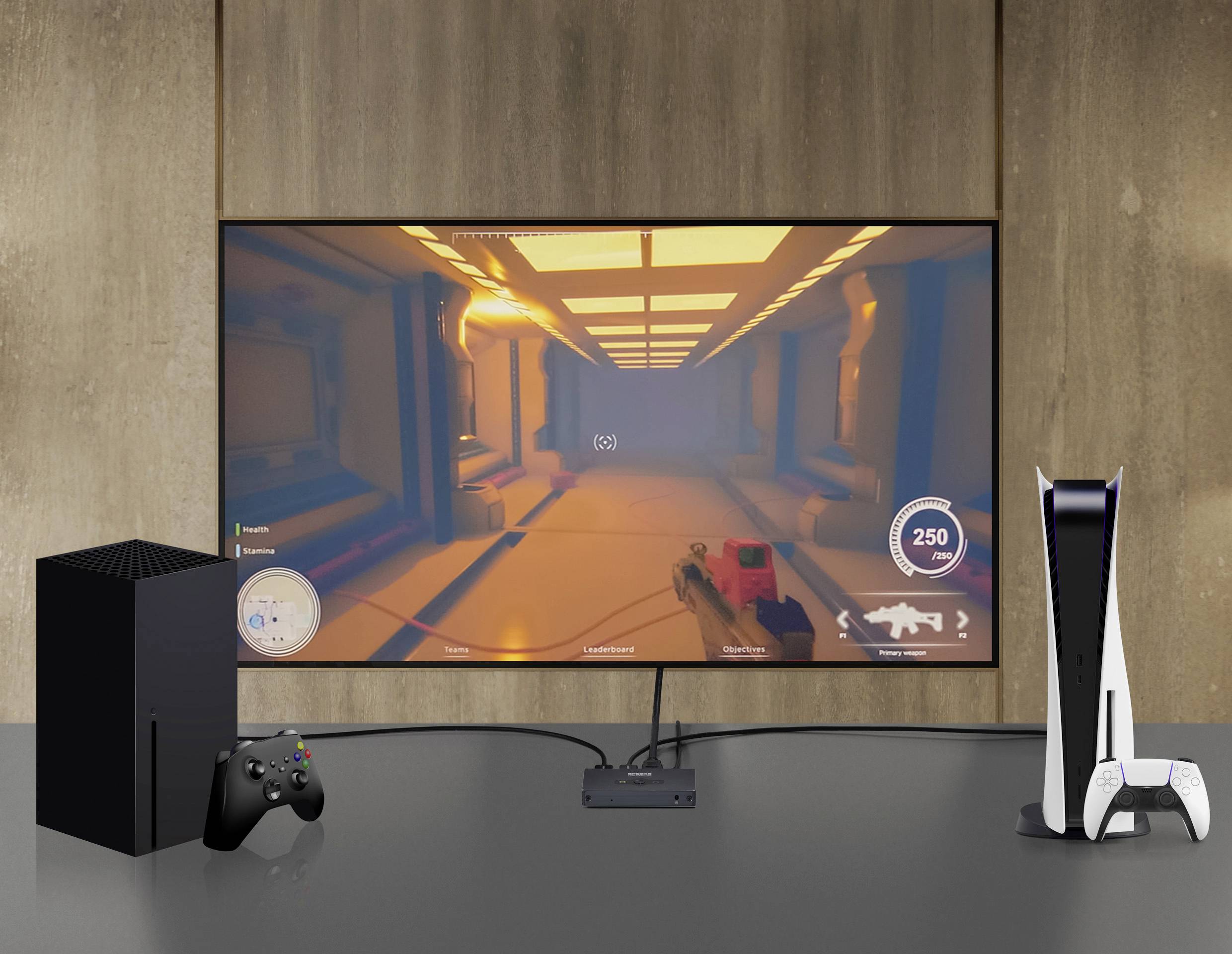 Televizor zobrazuje videohru v futuristické chodbě. Vedle něj stojí herní konzole s ovladačem a další konzole.