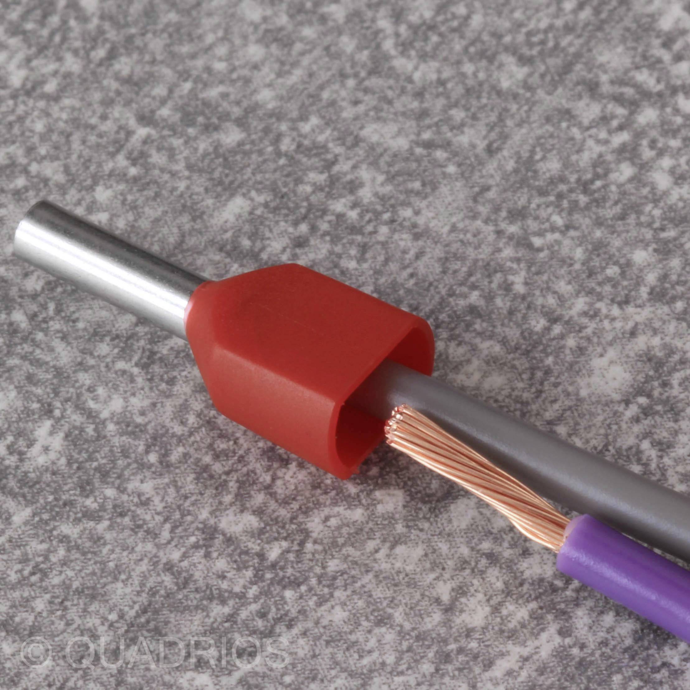 Elektrický kabel se staženou červenou izolací odhaluje měděné vodiče na šedém pozadí.