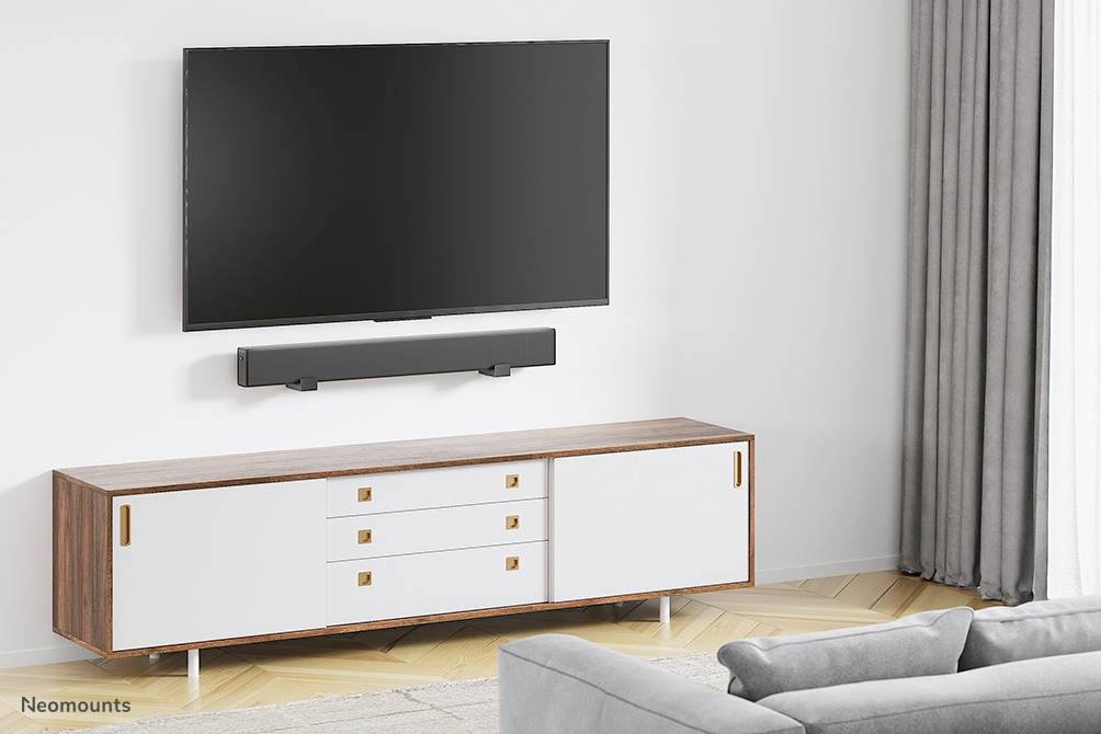 Obývací pokoj s televizí namontovanou na stěně nad soundbarem. Pod ním stojí moderní, minimalistický nízký TV stolek.