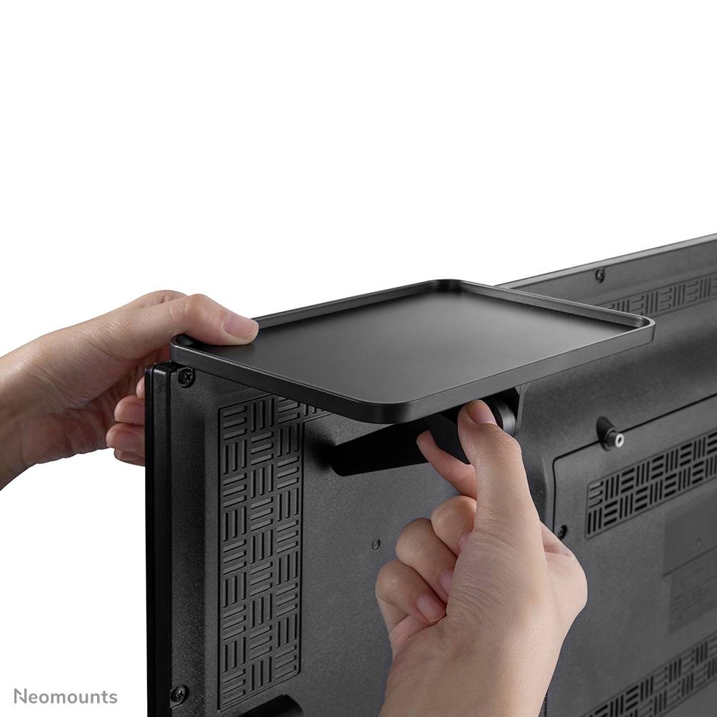 Ruce montují plochý regál na zadní stranu monitoru nebo televize.