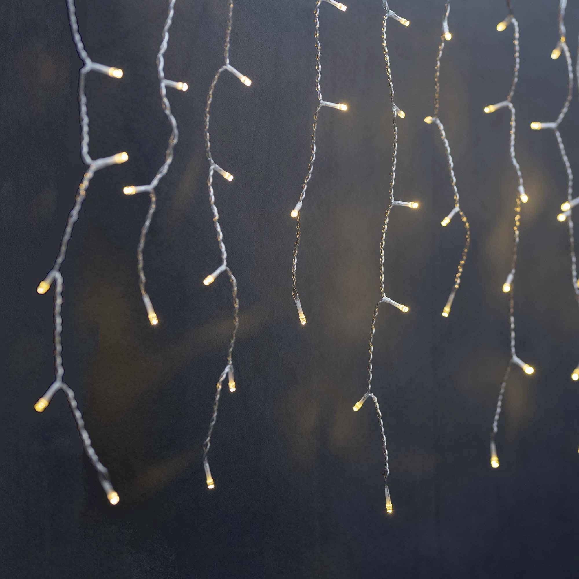 Světelné řetězy visí shora a svítí teplým žlutým odstínem, vytvářejí útulnou a slavnostní atmosféru.