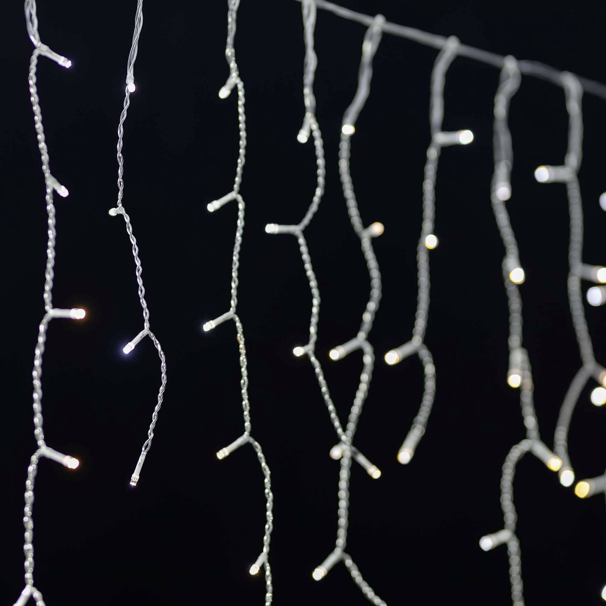 Světelné řetězy visí v několika řadách před tmavým pozadím. Světla jemně svítí a vytvářejí slavnostní atmosféru.