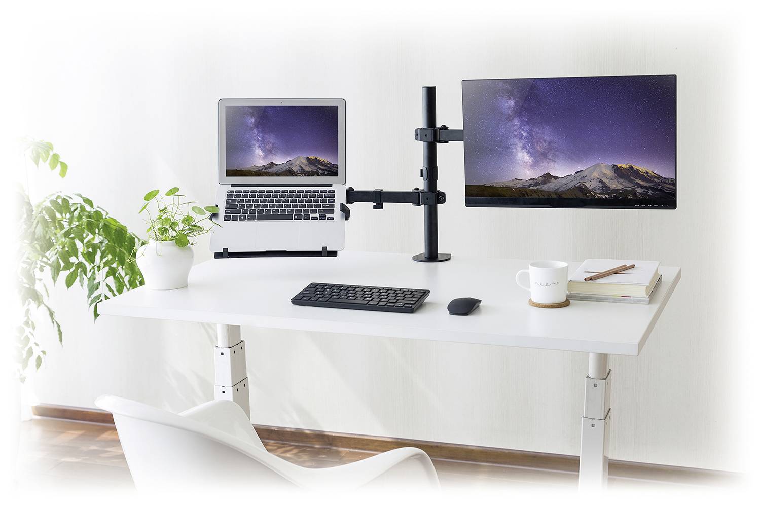 Moderní pracoviště se dvěma monitory, laptopem a klávesnicí na bílém psacím stole. Vedle stojí rostlina.