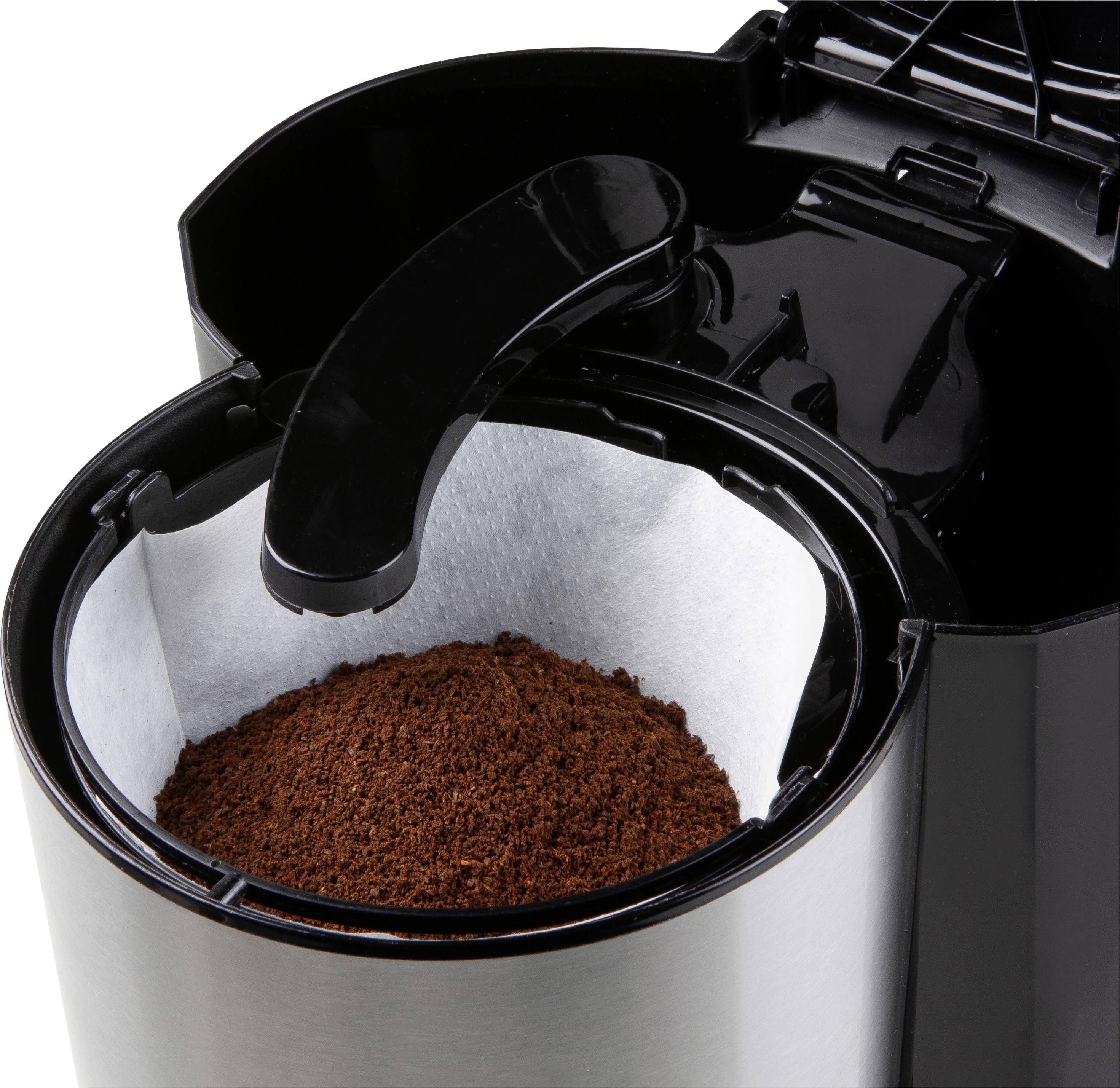 Kávový přístroj s otevřeným víkem zobrazuje mletou kávu ve filtru. Nahoře se nachází černá rukojeť pro ovládání.