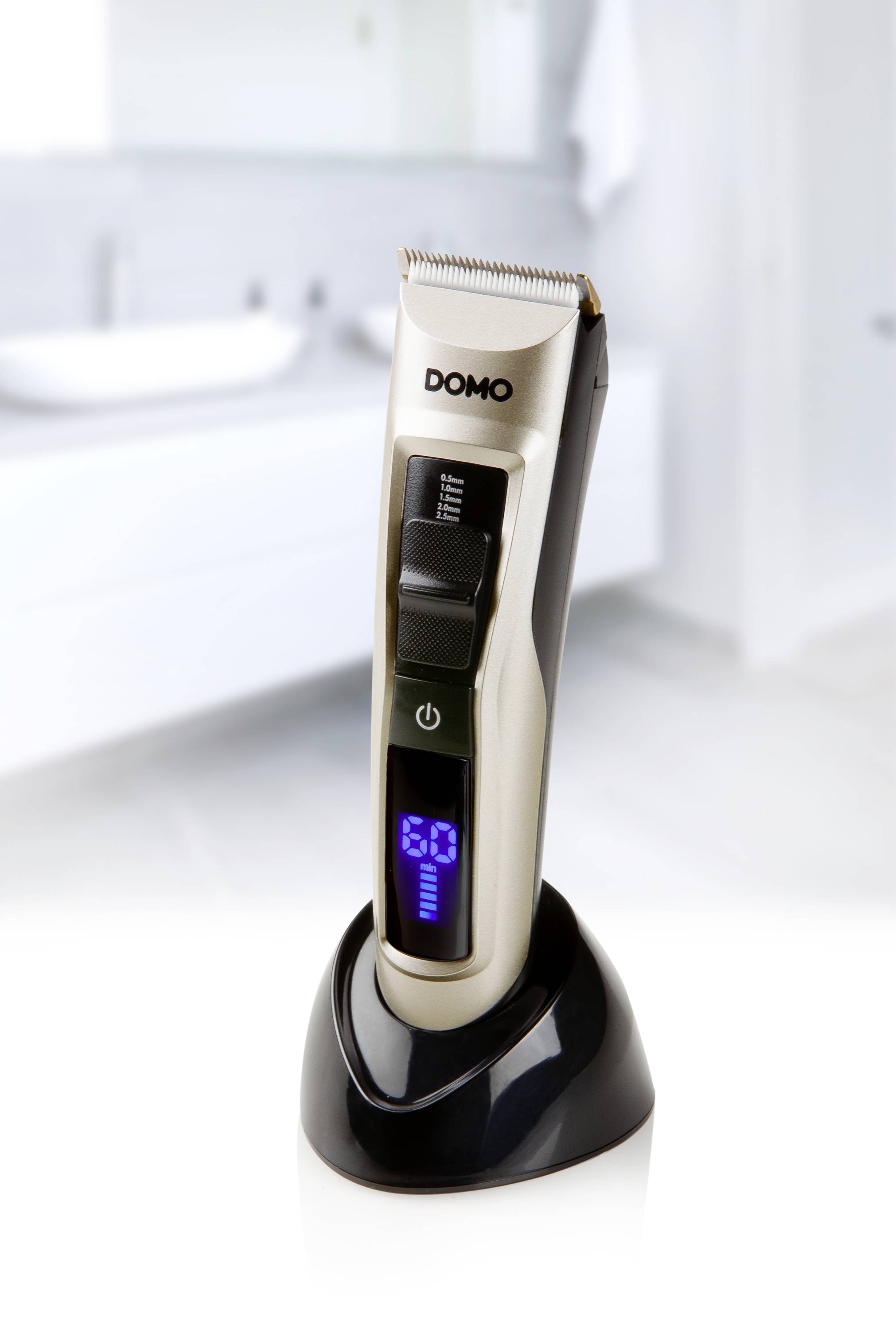 Elektrický zastřihovač vlasů s digitálním displejem na nabíjecí stanici, v pozadí rozmazané koupelny.