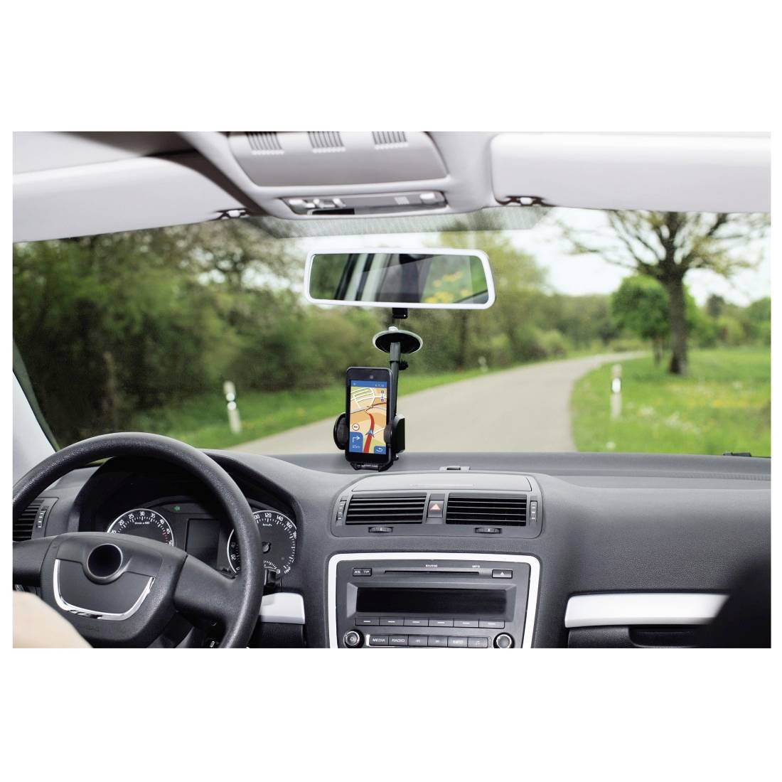 Pohled zevnitř automobilu, zobrazující upevněný smartphone s navigační aplikací otevřenou na venkovské silnici.