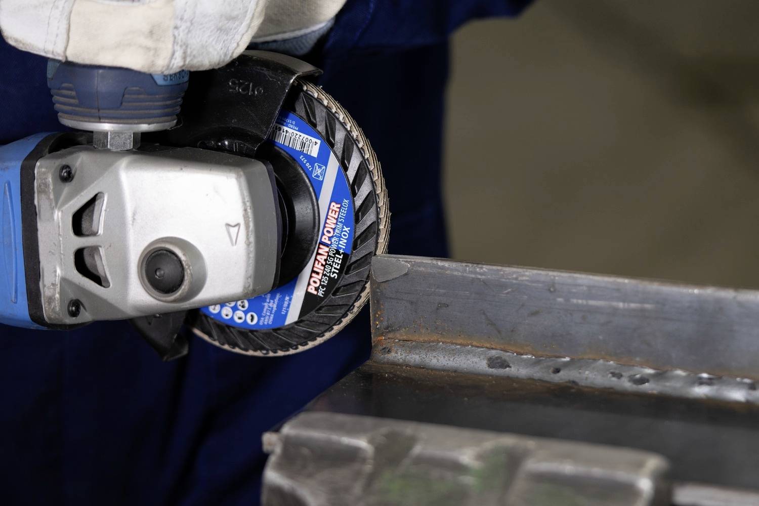 Dělník brousí kovovou hranu úhlovou bruskou. V detailním záběru létají jiskry.