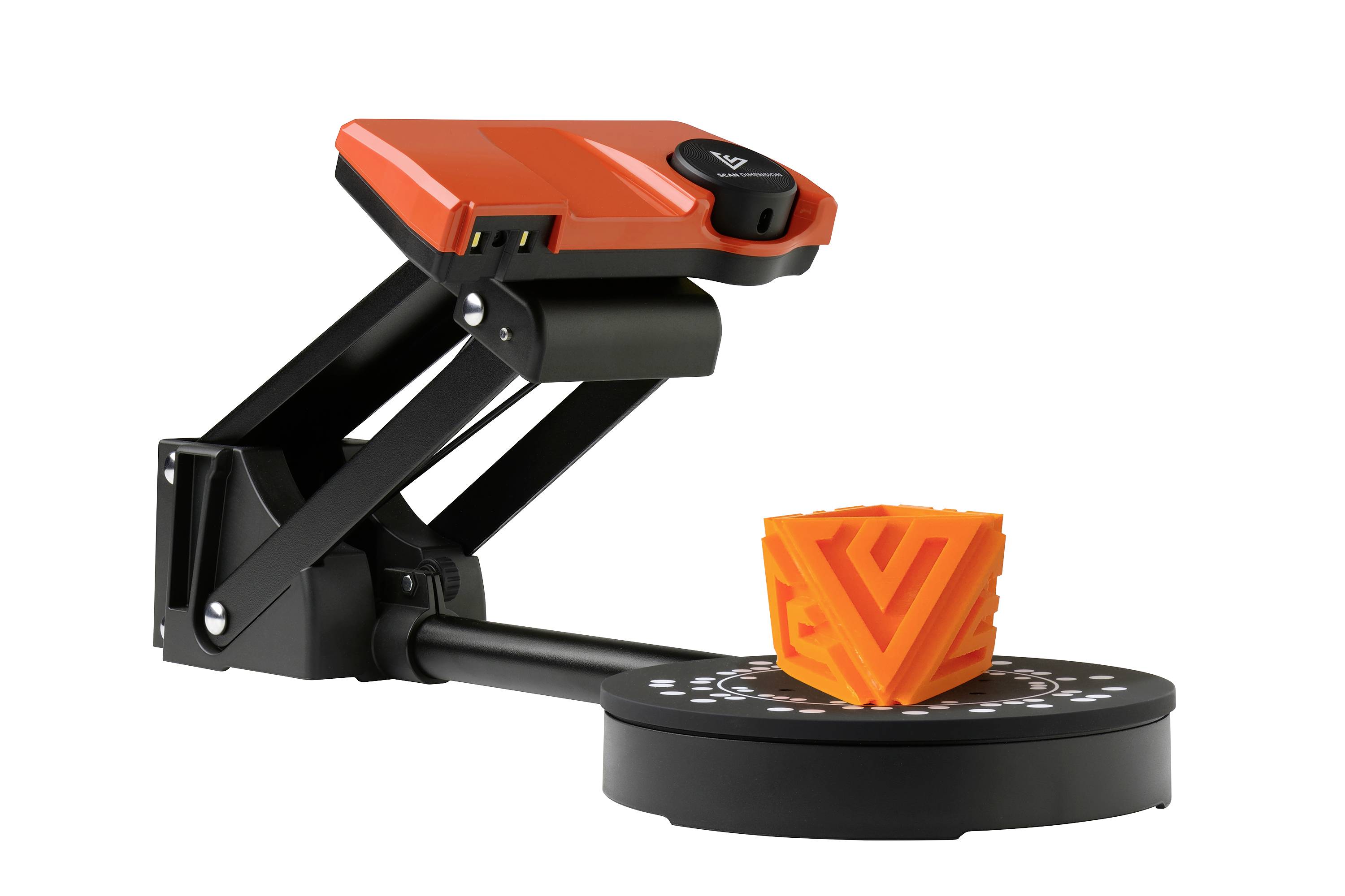 3D skener s červeným pouzdrem zachycuje oranžový geometrický objekt na otočném stolku.