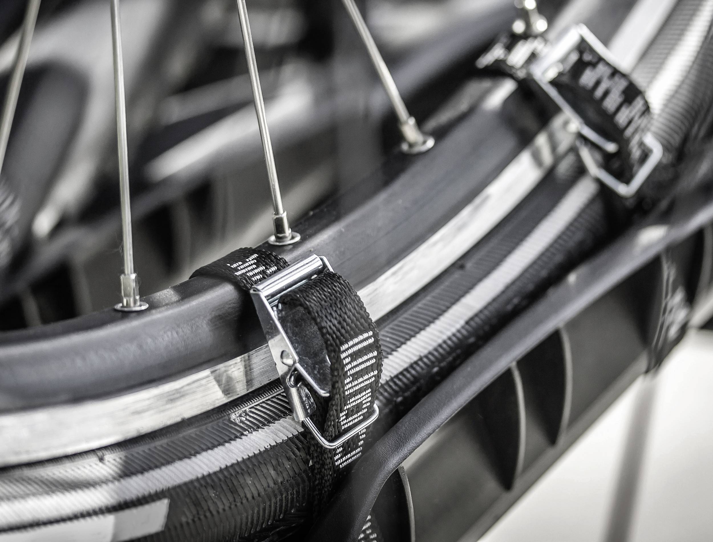 Detailní záběr cyklistické pneumatiky s kovovým ráfkem a černými obručemi zajišťujícími pneumatiku. Stříbrné dráty jsou viditelné.