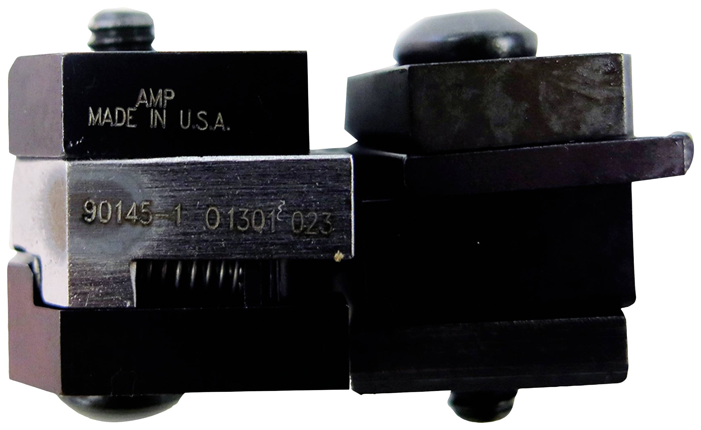 Logo 'AMP' a 'MADE IN U.S.A.' na tmavém kovovém nástroji se šrouby a pružinami, který drží nebo podporuje přesné díly.