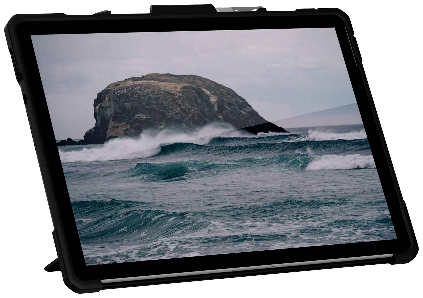 Tablet zobrazuje obraz bouřlivých vln narážejících na skalnatý útes pod zataženou oblohou.