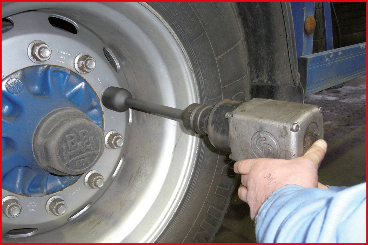 Mechanik utahuje šrouby nákladního vozu rázovým utahovákem. Zaměření je na pneumatiku a nástroj.