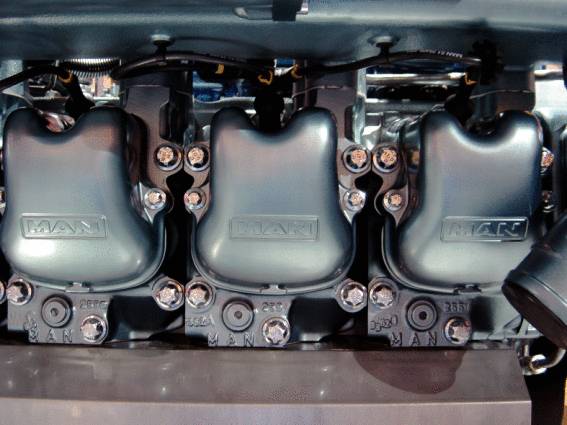 Tři válce motoru z kovu, velkého motoru, s označením 'MAN' na krytech.