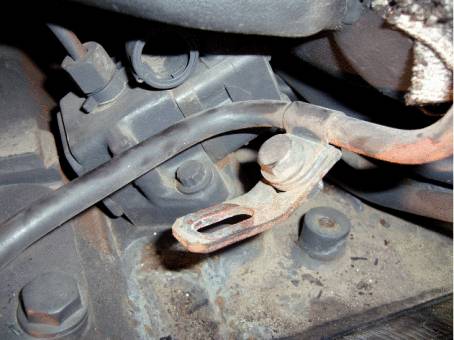 Zrezavělý připojovací bod pro kabel na stroji. V pozadí jsou vidět další mechanické součásti.