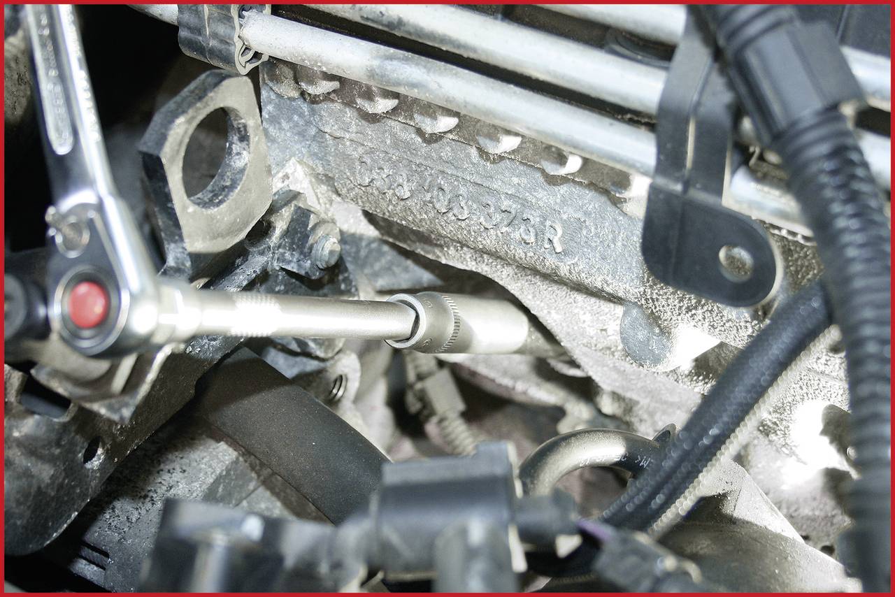 Horní strana motoru s připojeným nástrojem pro opravu nebo údržbu. Kabely a části motoru jsou viditelné.