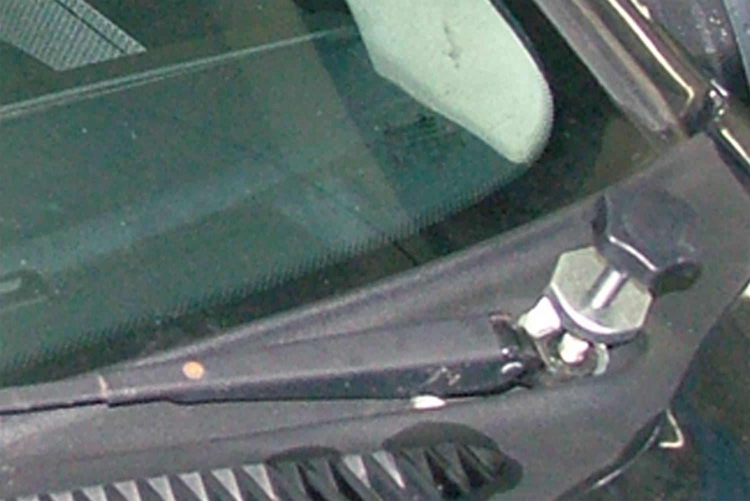 Stěrač namontovaný na autoskle, detailuchycení a ramene.