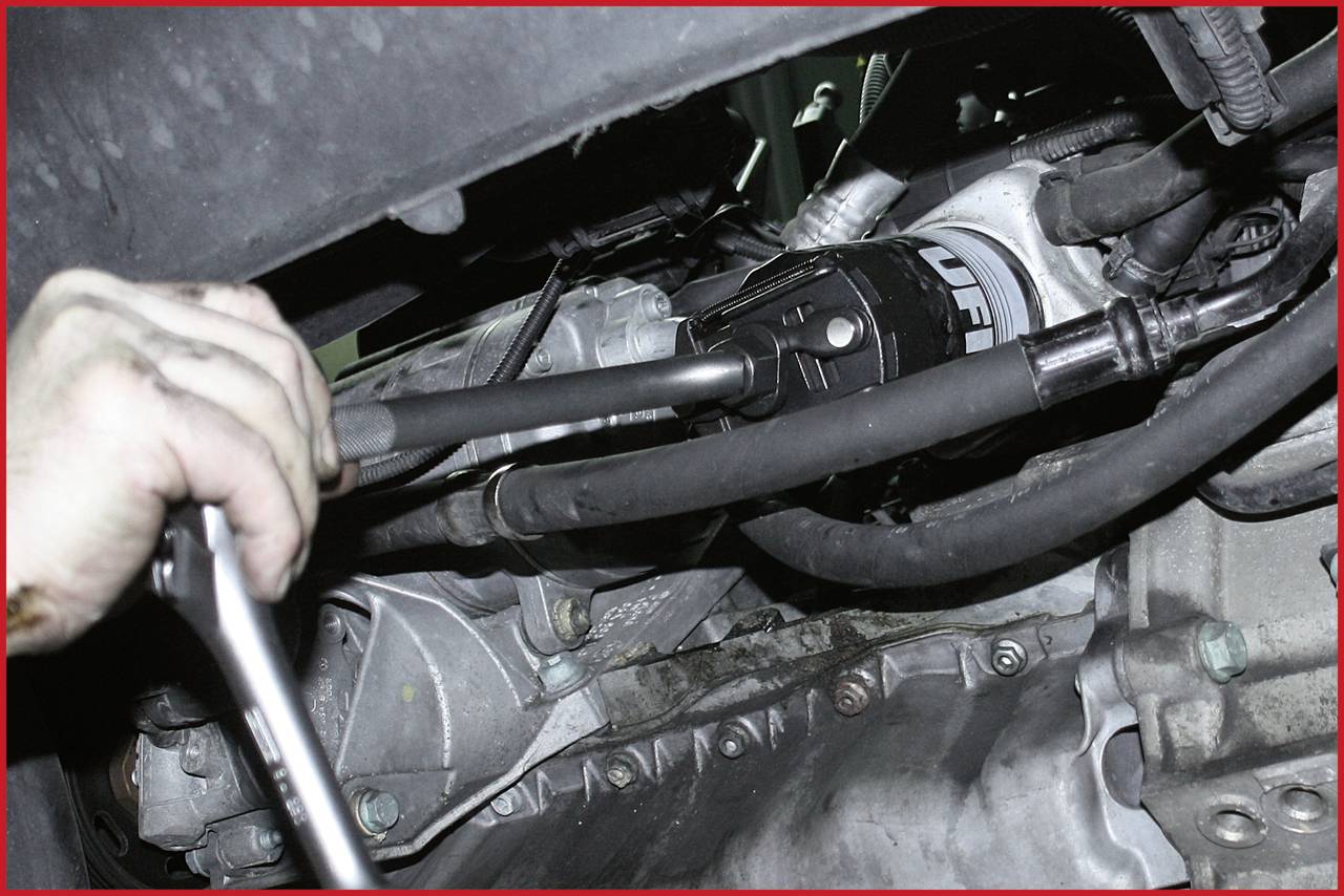 Mechanik používá klíč k práci na části motorového prostoru vozidla, plně ponořen do opravy.