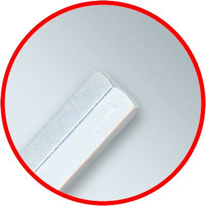 Detailní záběr šedého, protáhlého objektu na světlém pozadí, obklopeného červeným kruhem. Objekt je umístěn šikmo.