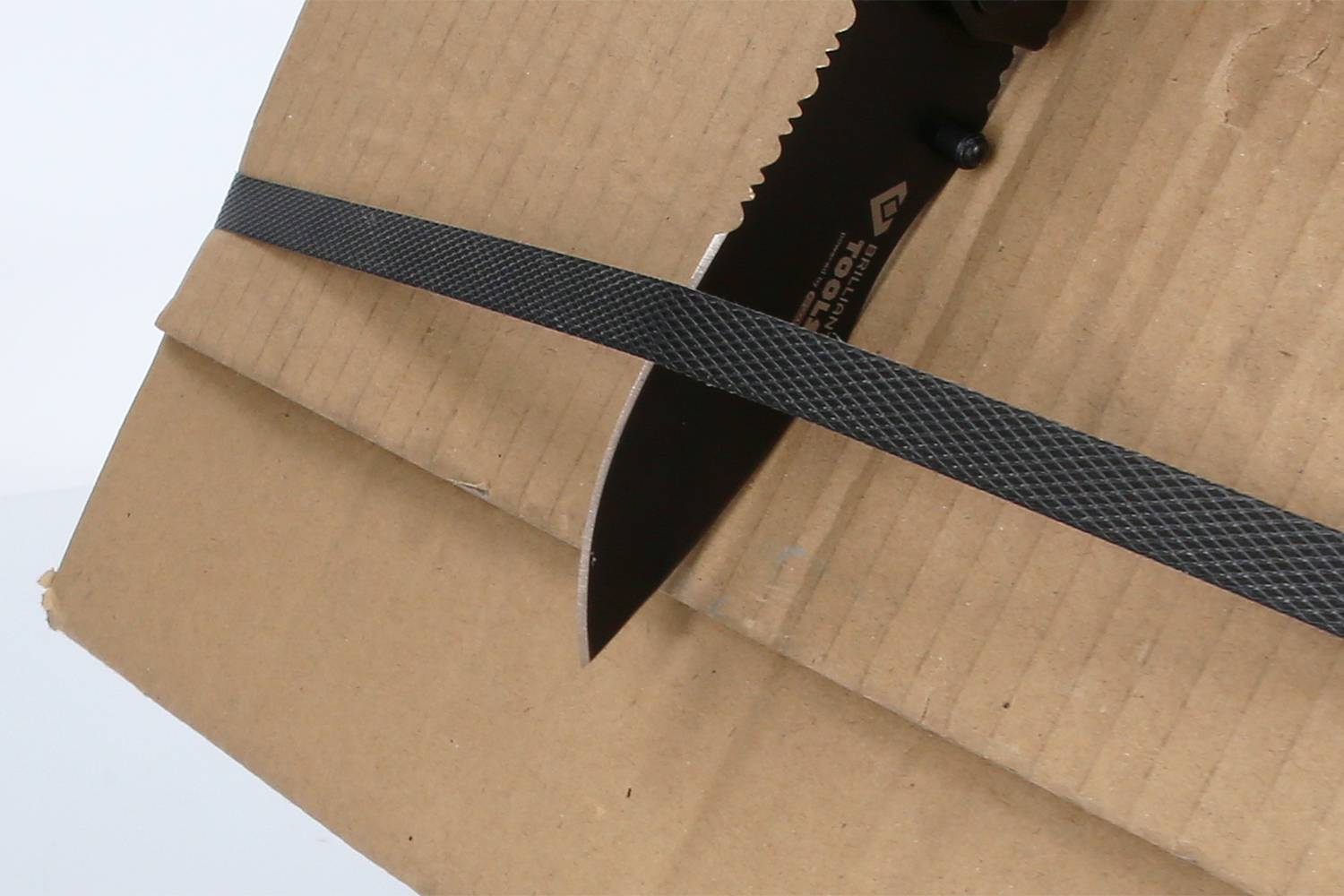 Karton je probodnut nožem. Přes karton je napnutý černý pás.