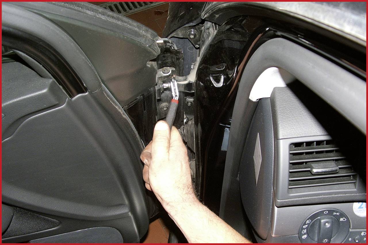 Jedna ruka drží šroubovací nástroj a upevňuje autodíl uvnitř vozu.