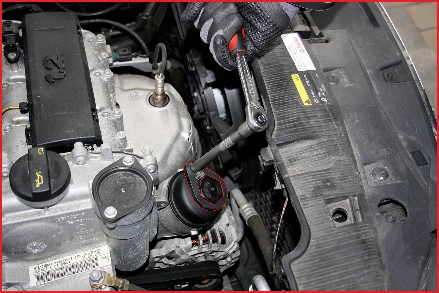Osoba obsluhuje klíčem víčko olejového filtru automobilu v motorovém prostoru. Soustředěná práce na motorovém vozidle.
