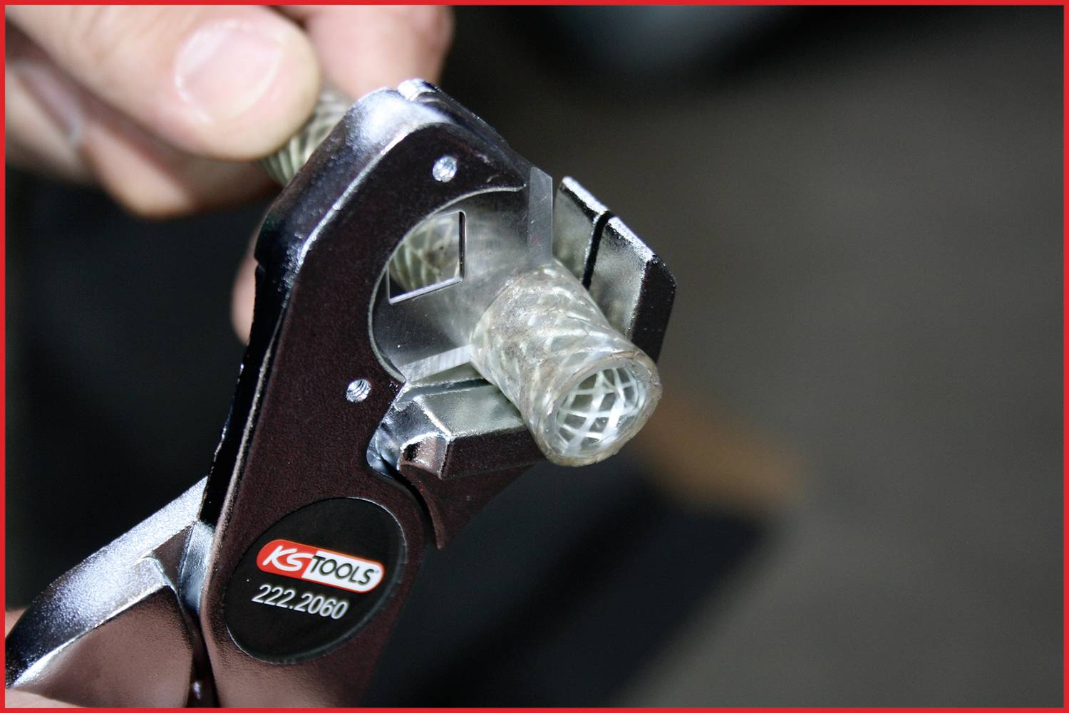Detailní záběr nástroje s nápisem 'KS TOOLS 222.2060', který drží kabelové vedení. Ruka drží nástroj.