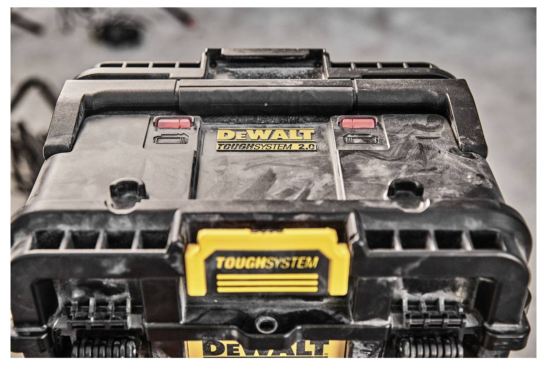 Černý box na nářadí od DeWalt ToughSystem 2.0 se viditelnými stopami od špíny a červenými zámky; důraz na odolnost.