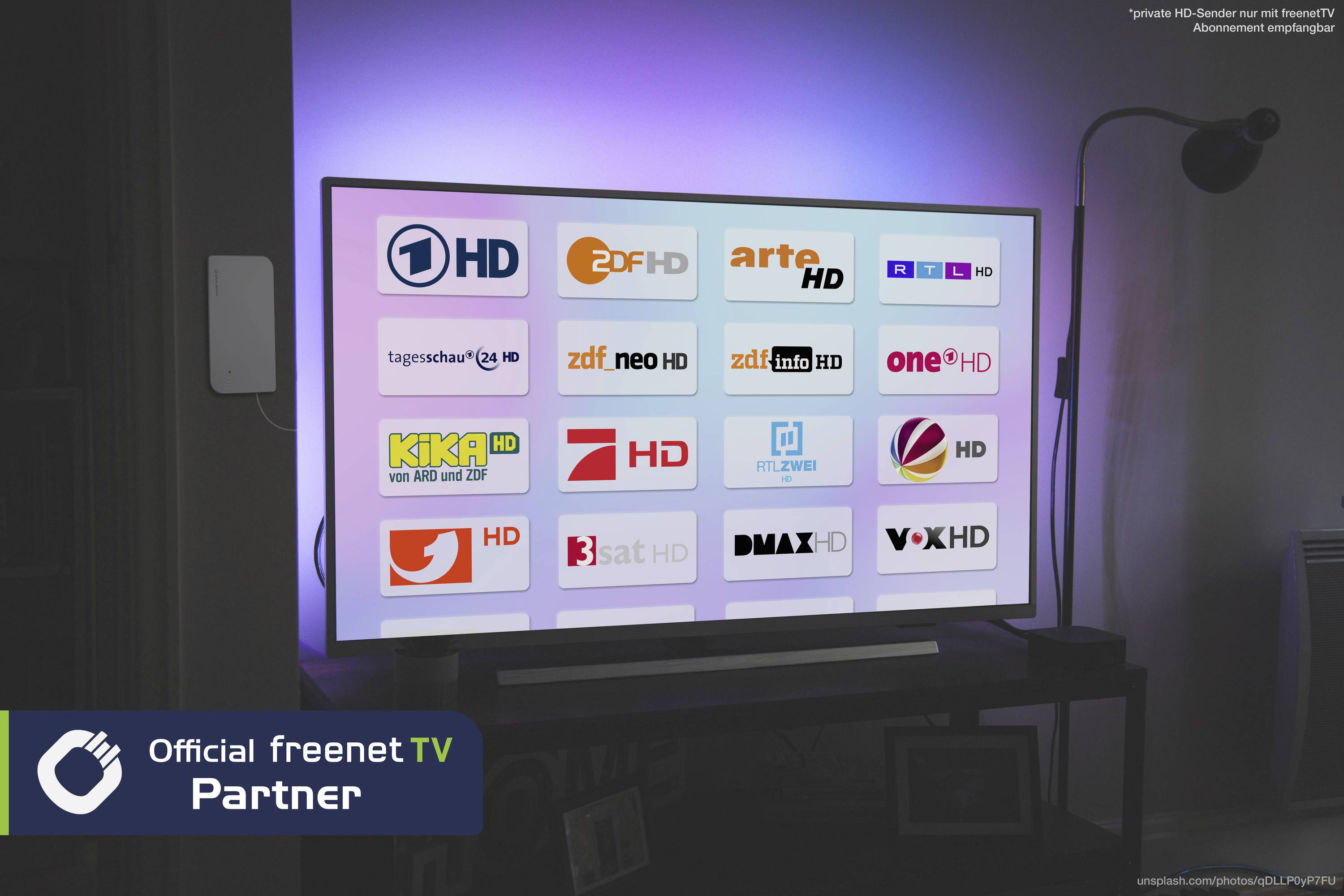 Televizor zobrazuje uživatelské rozhraní s logy různých německých televizních kanálů. V levém dolním rohu je viditelné logo 'Official freenet TV Partner'.