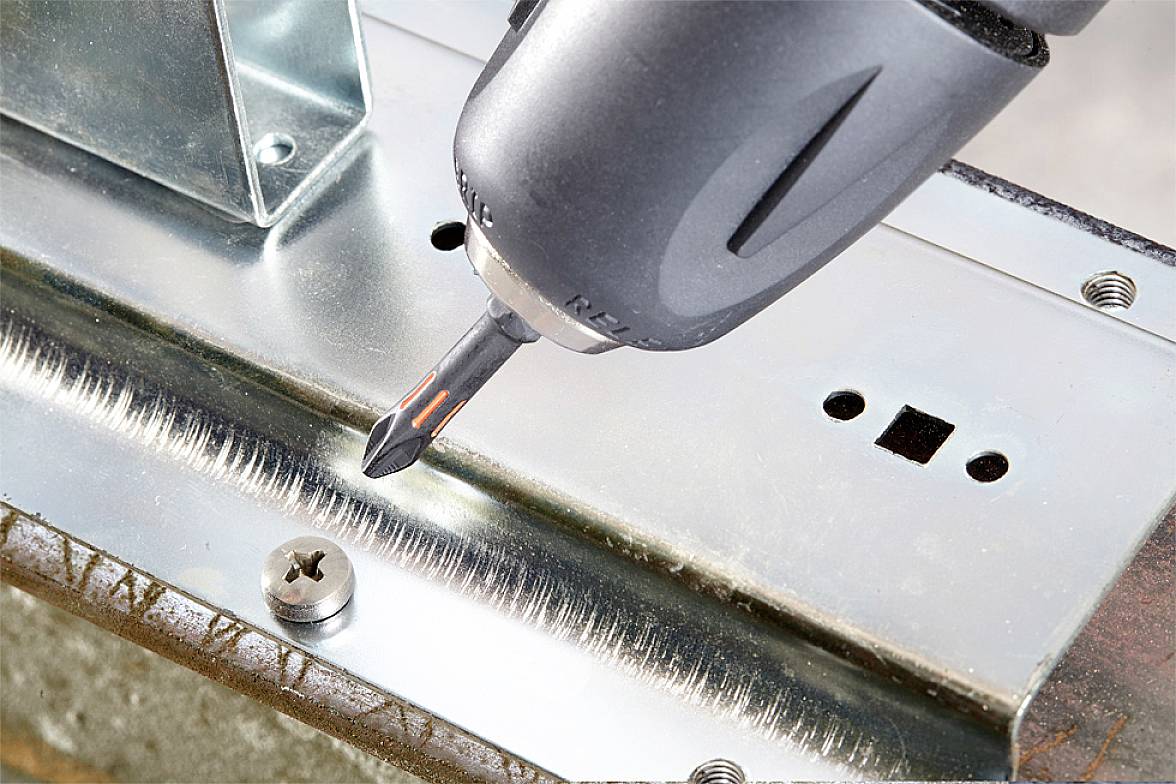 Elektrický šroubovák zatahuje šroub do kovového dílu.