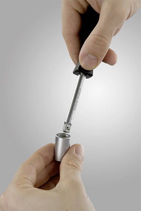 Jedna ruka drží kovový kontejner, zatímco druhá ruka do něj vkládá tyč nebo nástroj.