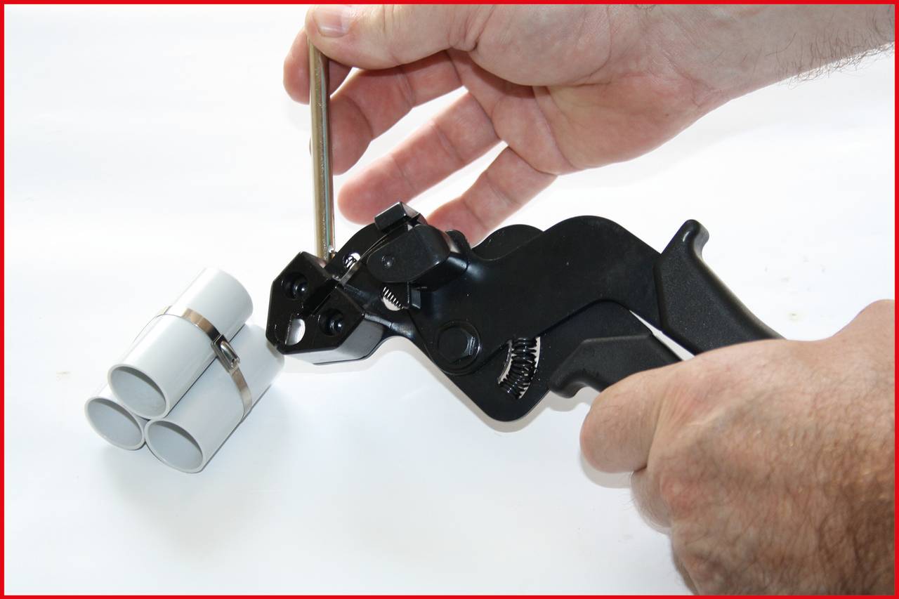 Jedna osoba utahuje stahovací pásky, aby svázala několik trubek dohromady.