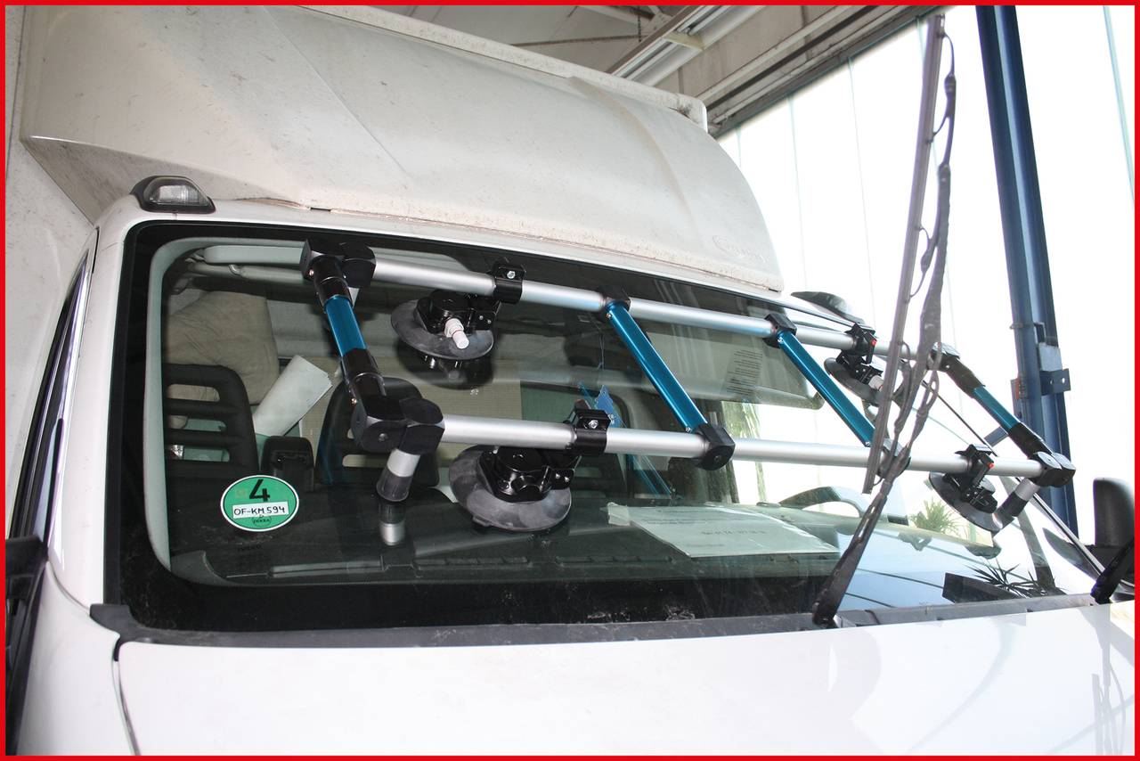 Zařízení s přísavkami je připevněno na čelním skle nákladního automobilu, pravděpodobně za účelem měření nebo kalibrace.
