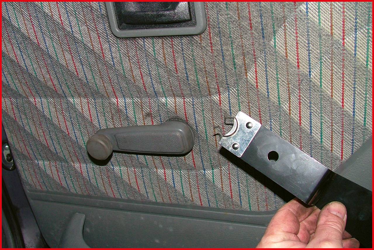 Někdo drží nástroj vedle čalounění automotivních dveří s mechanismem ručního ovládání okna.
