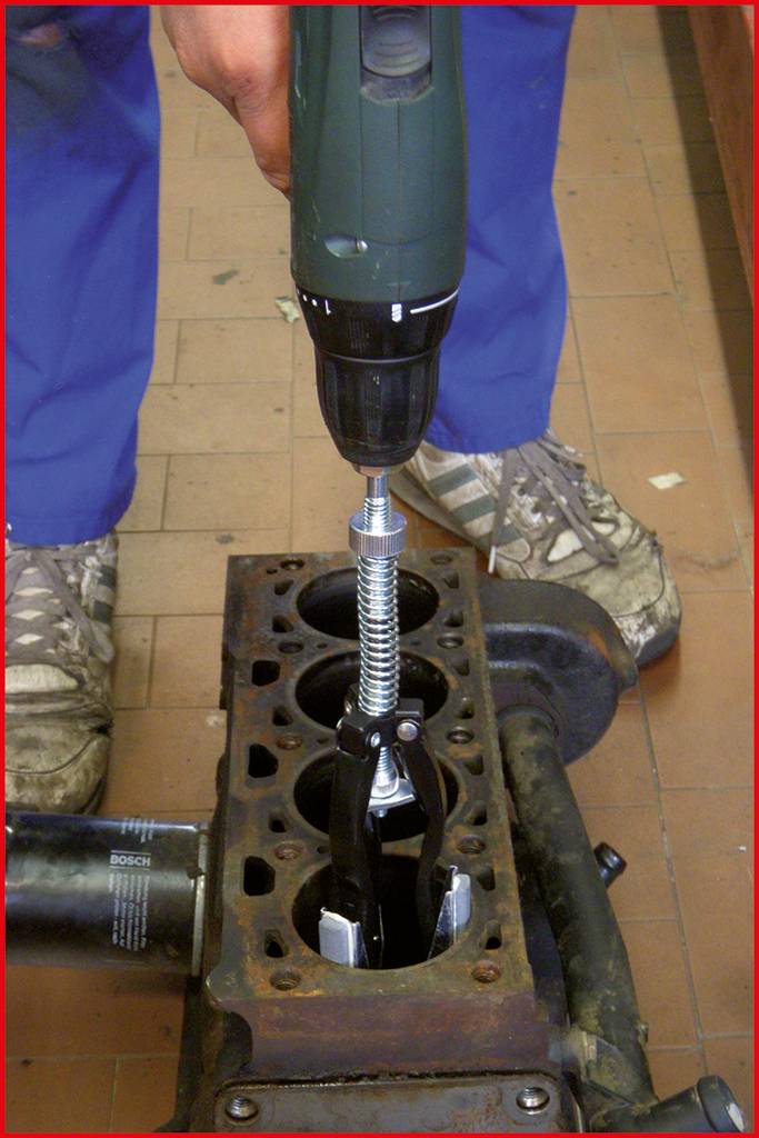 Mechanik používá vrtačku se speciálním vrtákem k opravě nebo obrábění části motoru.