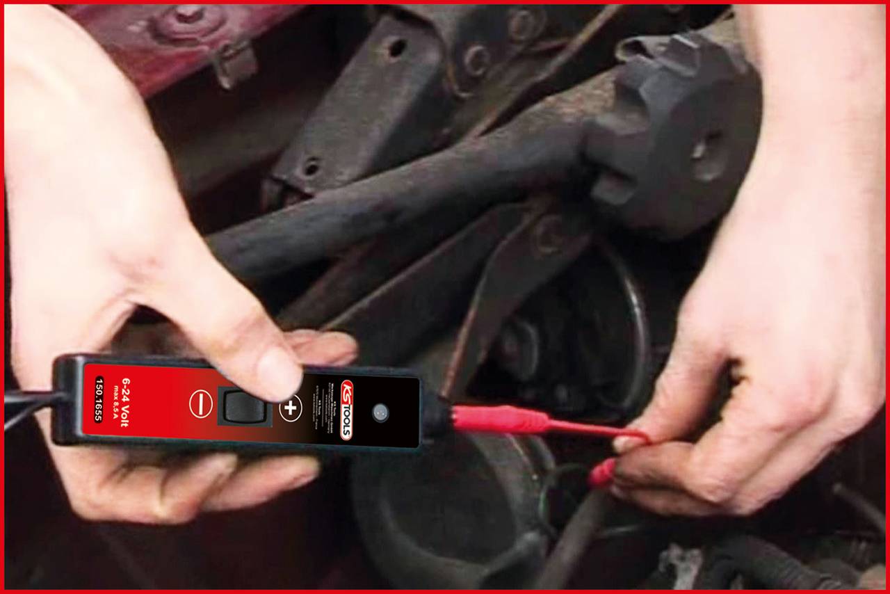 Osoba testuje kabelové připojení v automobilu pomocí elektrického testovacího zařízení. Ruce jsou v těsné blízkosti automobilové techniky.
