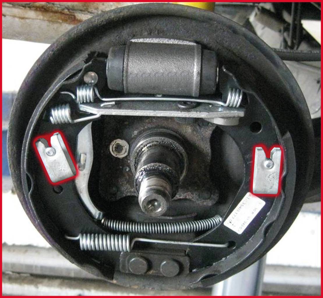 Bubnová brzda s brzdovými destičkami a pružinami v automobilu. Centrální hřídel je viditelná. Mechanické detaily jsou dobře rozeznatelné.