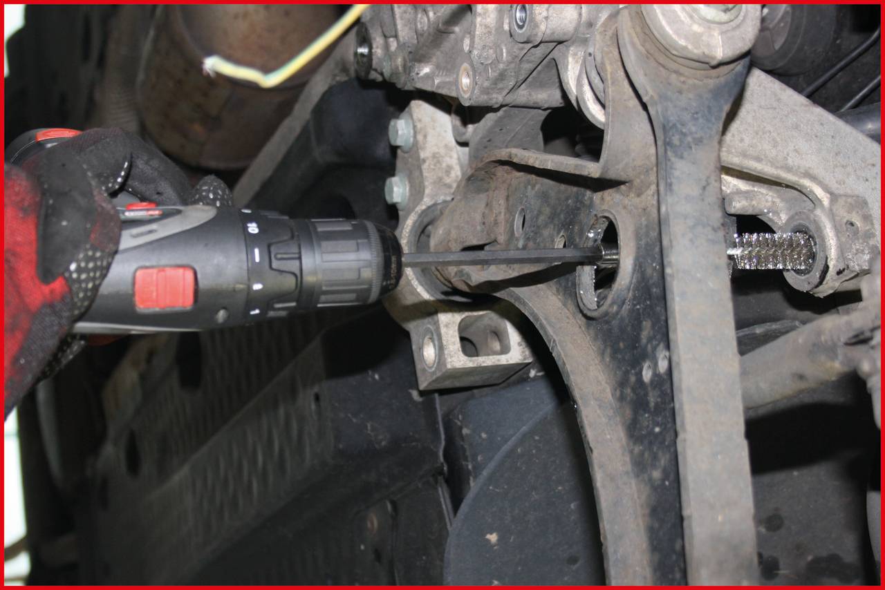 Osoba šroubuje elektrickou vrtačkou na části vozidla. Scéna ukazuje detailní záběr mechanických prací.