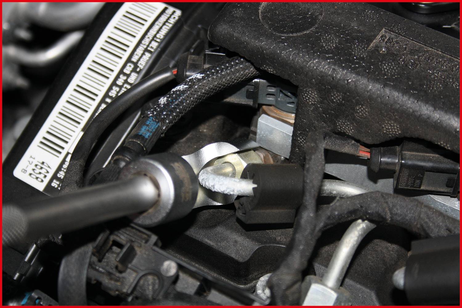 Detailní záběr motorové části automobilu s kabely a přípojkami, který zobrazuje propojovací body a detaily mechanických komponentů.